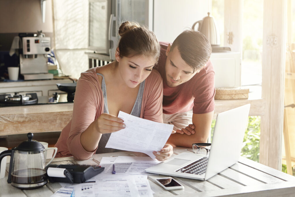 Young,Couple,Managing,Finances,,Reviewing,Their,Bank,Accounts,Using,Laptop