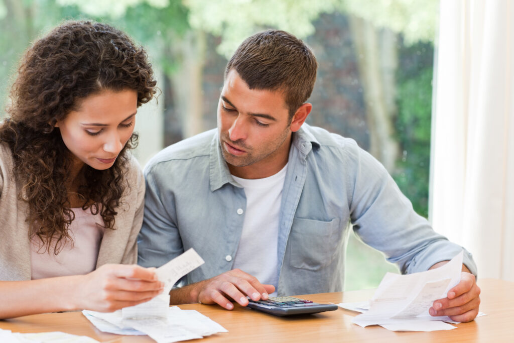 Young,Couple,Calculating,Their,Domestic,Bills,At,Home