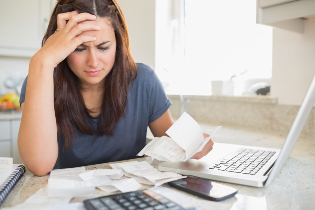 Brunette,Looking,Worried,Over,Bills,In,Kitchen.,Working,From,Home